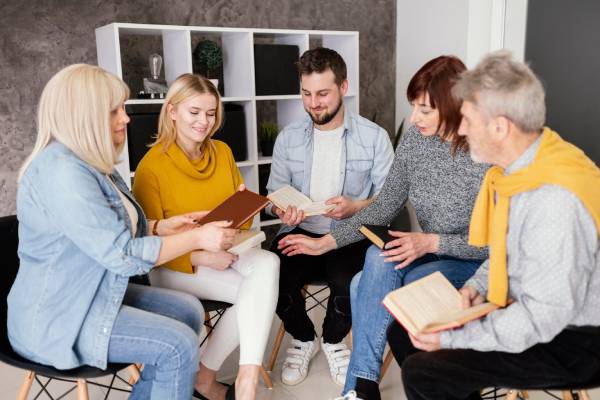 NDIS Group Activities: Adults reading and discussing books in a circle