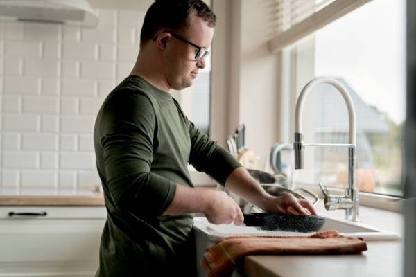 NDIS Household Task: Person with disability washing dishes in kitchen