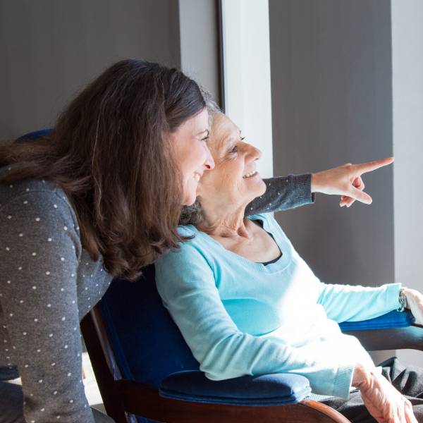 A young woman helps an elderly woman stand up as part of Personal Care Assistance