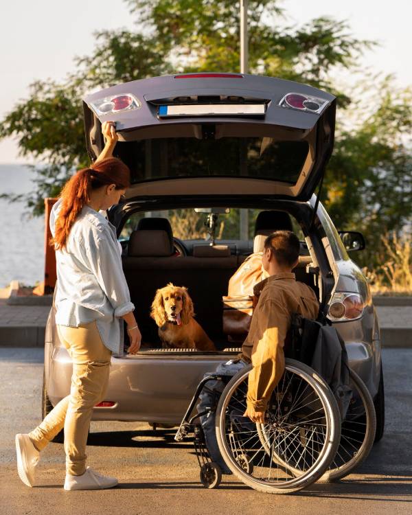 NDIS Transport Assistance: Person in wheelchair loads car with dog