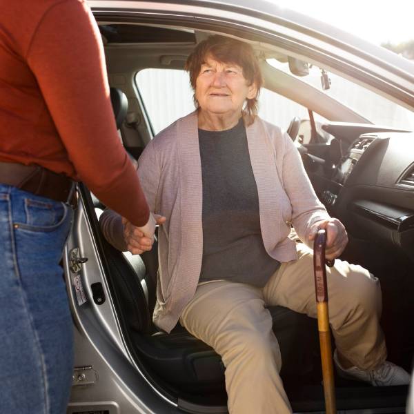 Support worker helps older woman into car